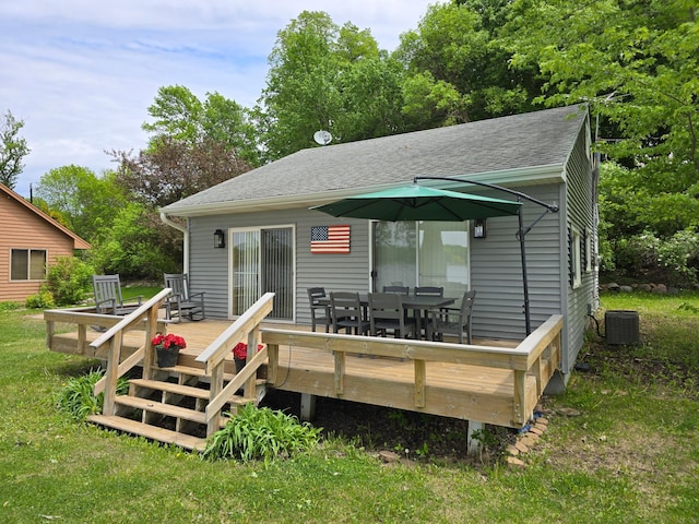 8137 Hoyt Ave SW, Victor Twp, MN 55349 - rear view of house with a deck, outdoor dining area, central AC, a shingled roof, and a lawn
