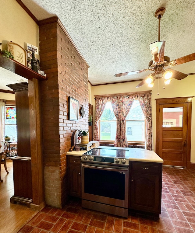 573 Rowland St, Tracy, MN 56175 - kitchen featuring stainless steel range with electric stovetop, a textured ceiling, ornamental molding, healthy amount of natural light, and light countertops