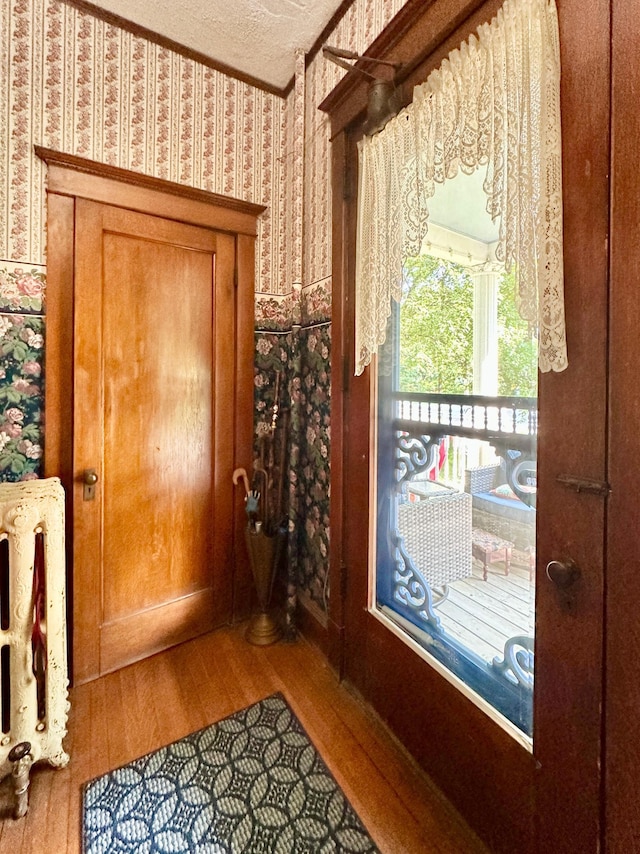 573 Rowland St, Tracy, MN 56175 - doorway featuring wallpapered walls, wood finished floors, a textured ceiling, and ornamental molding