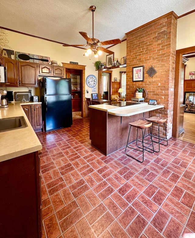 573 Rowland St, Tracy, MN 56175 - kitchen with freestanding refrigerator, brick patterned floors, a peninsula, a sink, and light countertops
