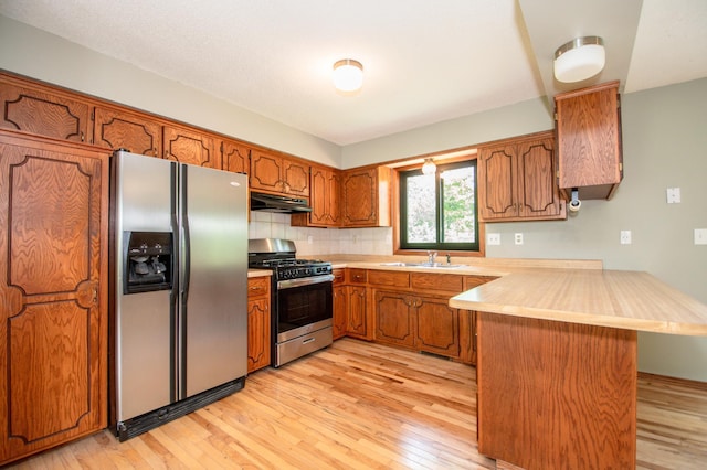 19715 Tyler St NW, Elk River, MN 55330 - kitchen with stainless steel appliances, a peninsula, under cabinet range hood, brown cabinets, and light countertops