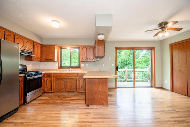 19715 Tyler St NW, Elk River, MN 55330 - kitchen featuring appliances with stainless steel finishes, under cabinet range hood, a peninsula, a sink, and brown cabinets