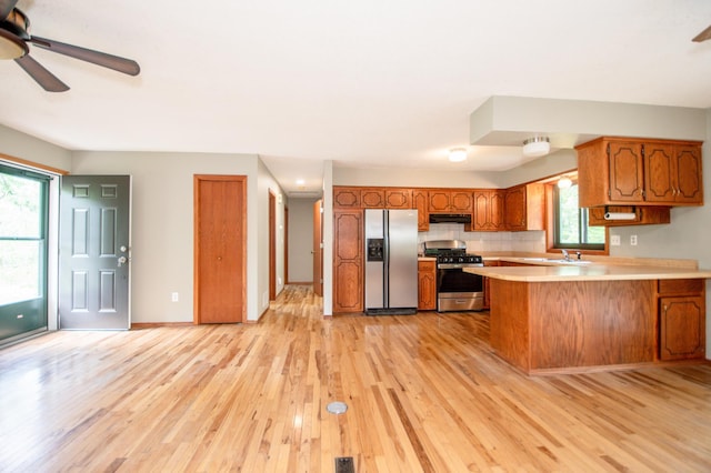 19715 Tyler St NW, Elk River, MN 55330 - kitchen featuring stainless steel appliances, brown cabinets, light wood finished floors, light countertops, and a peninsula