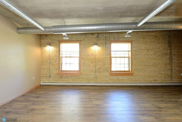 210 11th St N Unit 103, Fargo, ND 58102 - empty room featuring brick wall, wood finished floors, baseboards, a baseboard heating unit, and track lighting