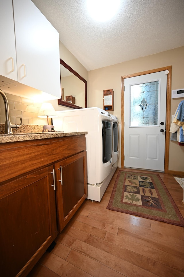 306 Windcrest Ln SE, New Prague, MN 56071 - laundry room with washer and dryer, cabinet space, light wood finished floors, and a textured ceiling