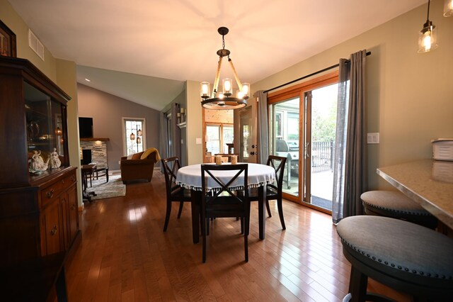 306 Windcrest Ln SE, New Prague, MN 56071 - dining space with plenty of natural light, a chandelier, a fireplace, dark wood-style flooring, and lofted ceiling