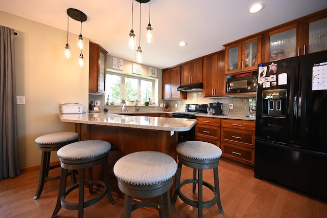306 Windcrest Ln SE, New Prague, MN 56071 - kitchen with black appliances, under cabinet range hood, light wood-style flooring, a sink, and a peninsula