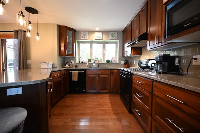 306 Windcrest Ln SE, New Prague, MN 56071 - kitchen with black appliances, under cabinet range hood, light wood finished floors, light stone countertops, and a peninsula