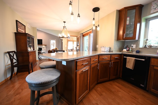 306 Windcrest Ln SE, New Prague, MN 56071 - kitchen with black dishwasher, a peninsula, wood finished floors, a kitchen bar, and glass insert cabinets