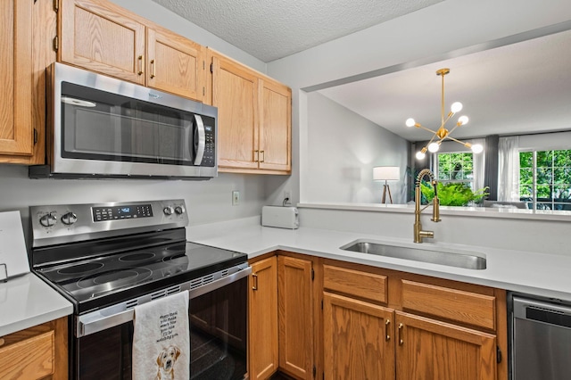 1925 Shenandoah Ct Unit F, Plymouth, MN 55447 - kitchen with stainless steel appliances, a sink, light countertops, hanging light fixtures, and a textured ceiling
