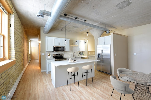 210 11th St N Unit 202, Fargo, ND 58102 - kitchen with stainless steel appliances, an island with sink, a breakfast bar, light wood-style flooring, and white cabinets