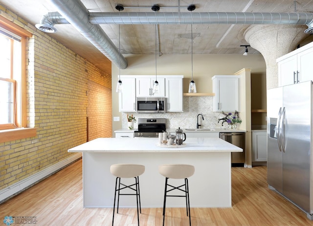 210 11th St N Unit 202, Fargo, ND 58102 - kitchen with stainless steel appliances, a sink, brick wall, light wood finished floors, and a kitchen bar