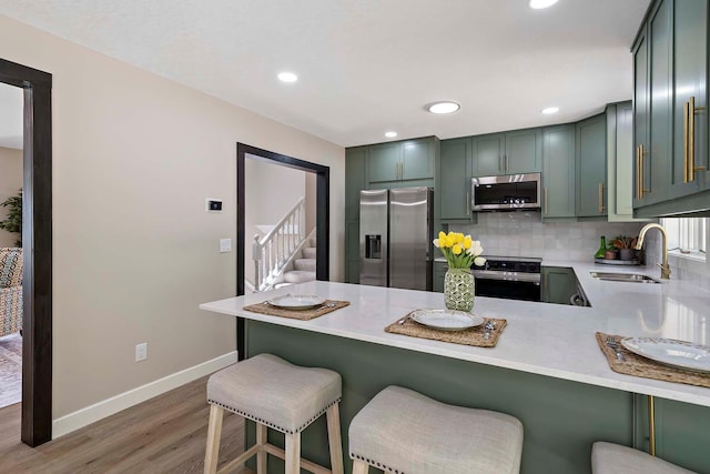 77 Emerson Ave W, West Saint Paul, MN 55118 - kitchen with stainless steel appliances, a sink, wood finished floors, a peninsula, and baseboards