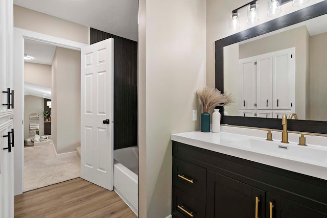 77 Emerson Ave W, West Saint Paul, MN 55118 - bathroom featuring wood finished floors, vanity, a tub to relax in, and baseboards