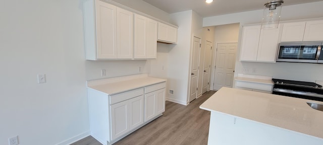 kitchen featuring stainless steel microwave, light wood-type flooring, baseboards, light countertops, and recessed lighting