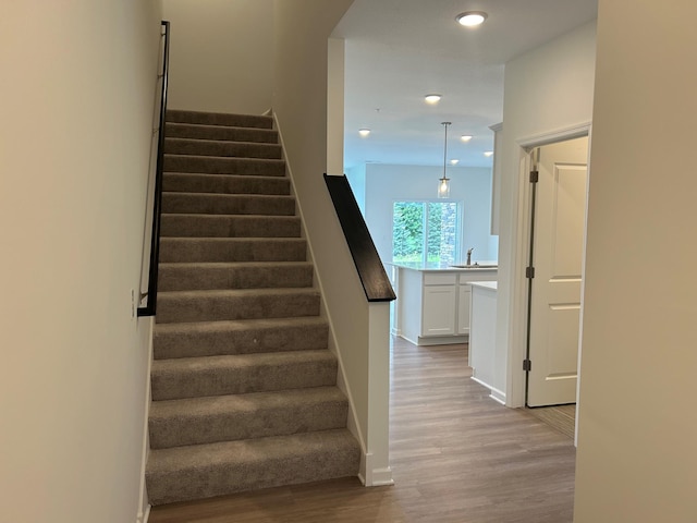 stairs featuring wood finished floors, recessed lighting, and baseboards