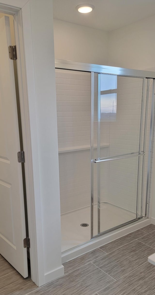 full bath featuring a stall shower, baseboards, wood finished floors, and recessed lighting