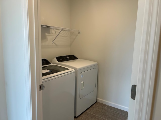 laundry room featuring washer and dryer, baseboards, and dark wood finished floors