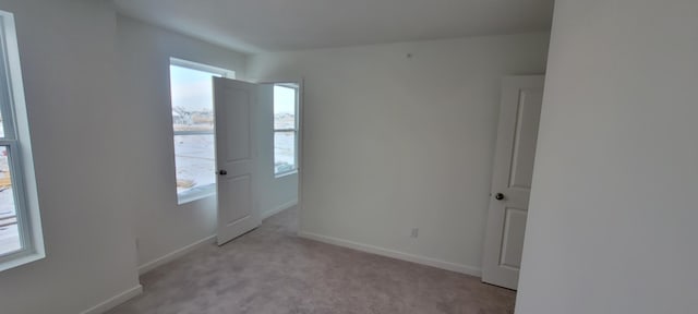 spare room with light carpet and baseboards