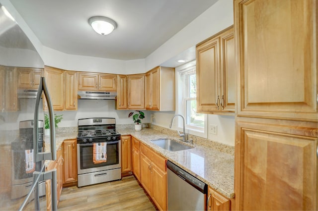 2714 18th Ave S, Minneapolis, MN 55407 - kitchen featuring appliances with stainless steel finishes, a sink, under cabinet range hood, light stone countertops, and light wood-style flooring