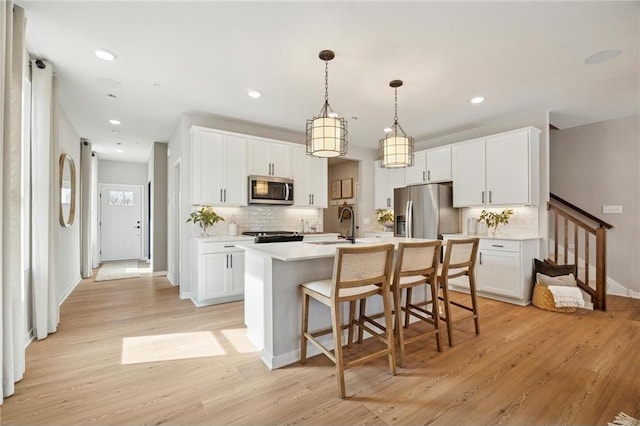 10391 Glacier Ln N, Maple Grove, MN 55369 - kitchen featuring stainless steel appliances, tasteful backsplash, light countertops, a center island with sink, and light wood-style floors