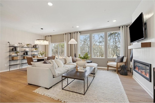 10391 Glacier Ln N, Maple Grove, MN 55369 - living area with baseboards, light wood finished floors, a glass covered fireplace, a chandelier, and recessed lighting
