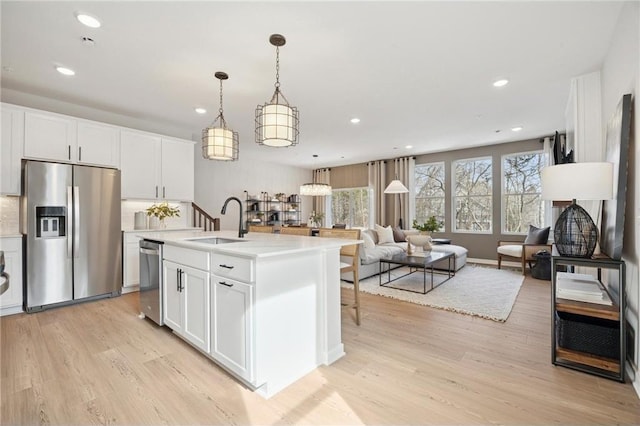 10391 Glacier Ln N, Maple Grove, MN 55369 - kitchen with appliances with stainless steel finishes, a sink, light wood-type flooring, open floor plan, and recessed lighting