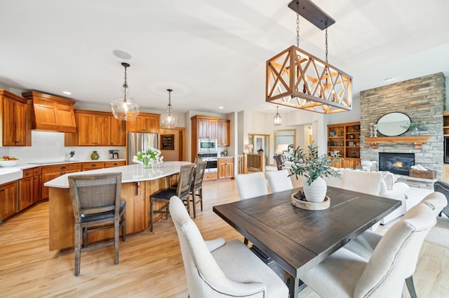 dining room with light wood finished floors, a fireplace, and recessed lighting