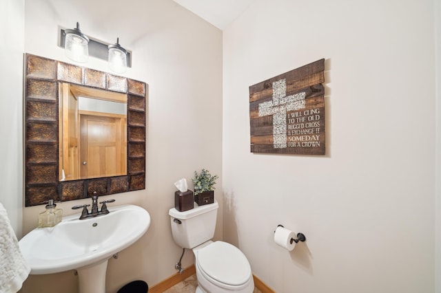 bathroom with a sink, toilet, and baseboards