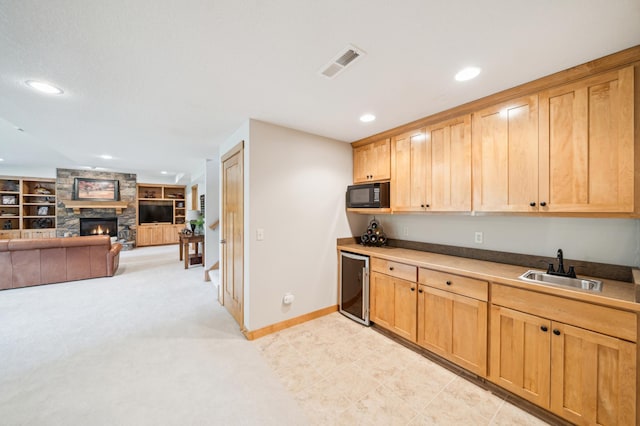 kitchen with black microwave, a sink, wine cooler, recessed lighting, and a fireplace