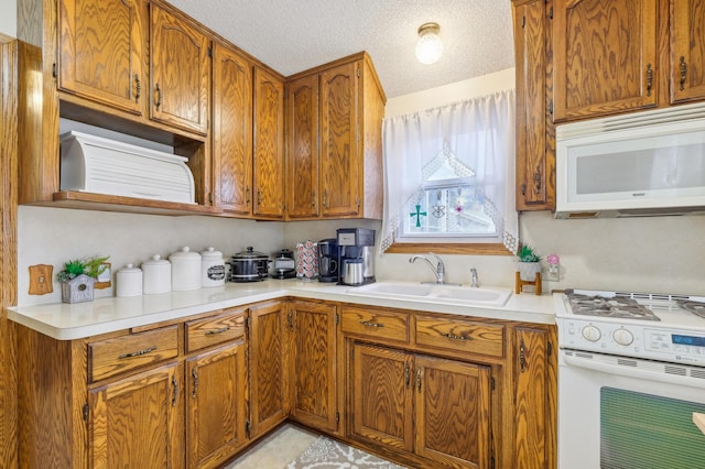 1224 Grotto St N, Saint Paul, MN 55117 - kitchen featuring white appliances, a sink, brown cabinetry, and a textured ceiling