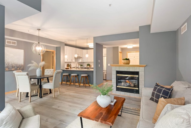 living area with light wood-style flooring, a tile fireplace, and baseboards