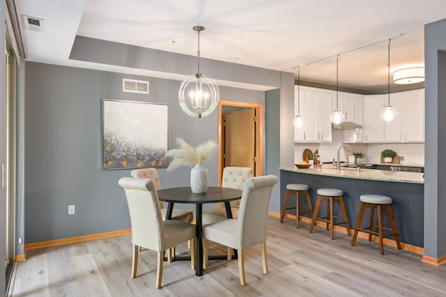 dining area featuring baseboards, a chandelier, and light wood-type flooring