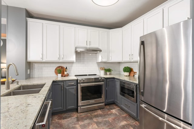kitchen with appliances with stainless steel finishes, under cabinet range hood, a sink, gray cabinetry, and white cabinetry