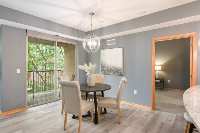 dining room with baseboards, light wood-type flooring, and a chandelier