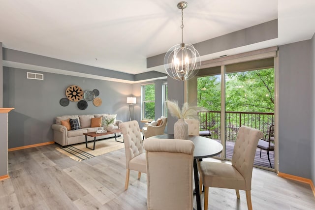 dining space featuring a chandelier, baseboards, and light wood-style flooring