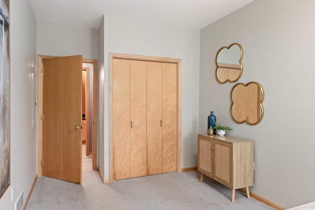 bedroom with light colored carpet, a closet, and baseboards