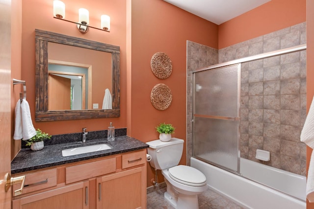 full bathroom featuring vanity, toilet, tile patterned flooring, and bath / shower combo with glass door