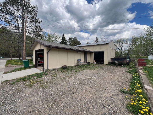 225 State St, Buhl, MN 55713 - view of side of property with an attached garage, an outbuilding, board and batten siding, and gravel driveway