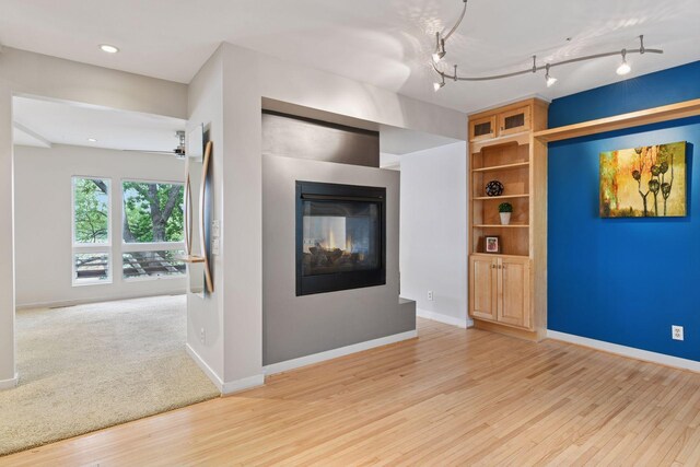 5016 Shady Oak Rd S, Minnetonka, MN 55343 - unfurnished living room with light wood-style flooring, a multi sided fireplace, rail lighting, baseboards, and recessed lighting