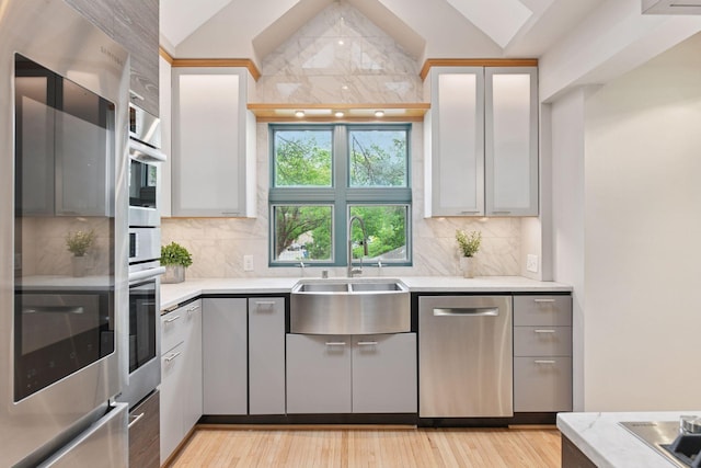 5016 Shady Oak Rd S, Minnetonka, MN 55343 - kitchen with dishwasher, a sink, decorative backsplash, vaulted ceiling, and light wood-style floors