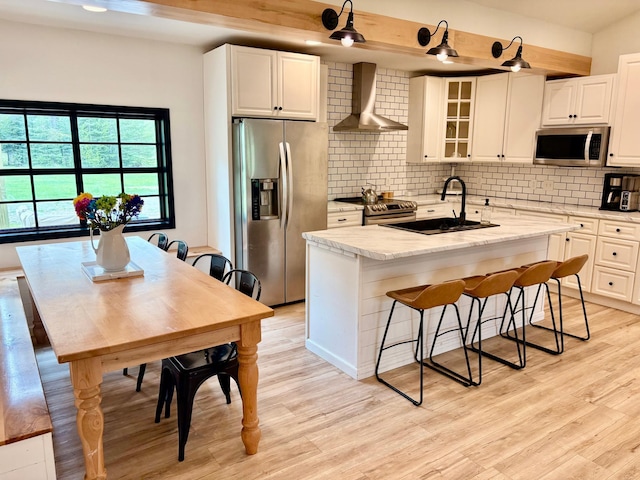 1622 82nd Ave NW, Williams, MN 56686 - kitchen with stainless steel appliances, wall chimney exhaust hood, a sink, light wood-type flooring, and a kitchen island with sink
