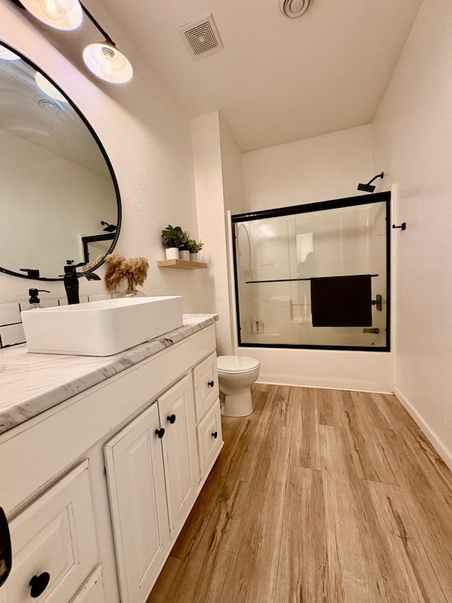 1622 82nd Ave NW, Williams, MN 56686 - full bathroom featuring wood finished floors, vanity, toilet, and combined bath / shower with glass door