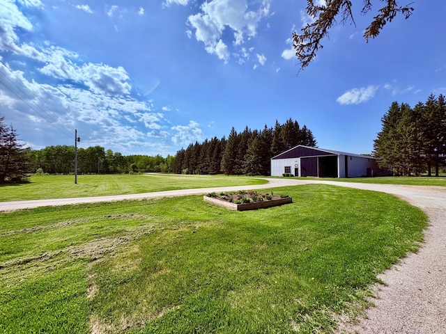1622 82nd Ave NW, Williams, MN 56686 - view of green lawn featuring a pole building, a garage, driveway, an outdoor structure, and a wooded view