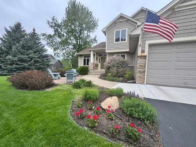 15224 Swallow St NW, Andover, MN 55304 - view of front of house with a garage, a front yard, driveway, and stone siding