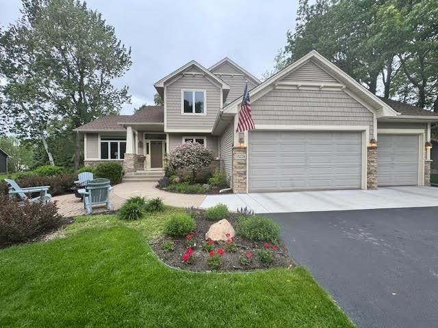 15224 Swallow St NW, Andover, MN 55304 - craftsman house featuring driveway, a garage, stone siding, and a front lawn