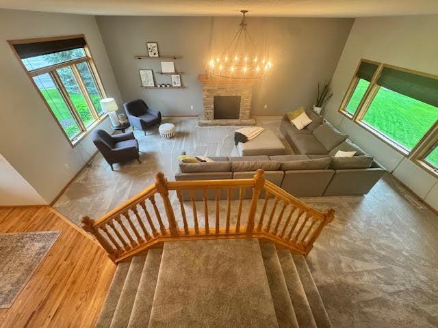 15224 Swallow St NW, Andover, MN 55304 - living room featuring wood finished floors, a brick fireplace, a chandelier, and stairway