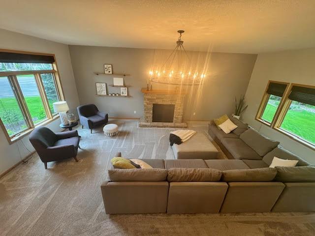 15224 Swallow St NW, Andover, MN 55304 - living room with carpet, a chandelier, a fireplace with raised hearth, and baseboards