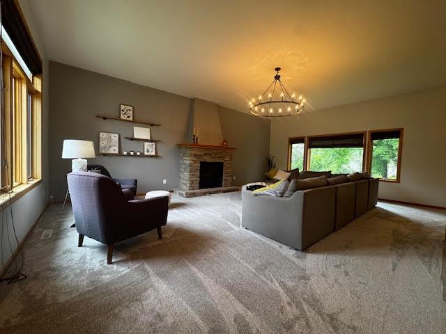15224 Swallow St NW, Andover, MN 55304 - living area featuring carpet floors, a chandelier, a fireplace with raised hearth, and baseboards