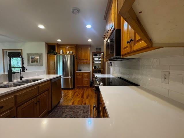 15224 Swallow St NW, Andover, MN 55304 - kitchen with appliances with stainless steel finishes, a sink, brown cabinetry, decorative backsplash, and dark wood-style floors